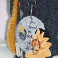 This handbag also has an attachable keychain on the side, which contains a blue male moon and star masquerade mask and a yellow female sun masquerade mask. There are also three crystals hanging to the bottom left and the quote "You Remind Me That I'm Alive" written between the two masks. 
